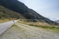 a motorcycle parked on a small mountain side road near mountains with no cars driving on it