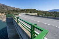 the roadway of a highway with a bike bridge over the river bank and mountains in the distance