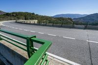 the roadway of a highway with a bike bridge over the river bank and mountains in the distance