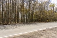 a lone motorcycle rides along an empty roadway with trees in the background in this image