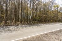 a lone motorcycle rides along an empty roadway with trees in the background in this image