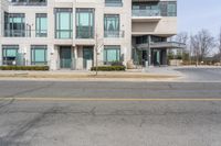 an empty street in front of a modern apartment building with balconies on the first floor