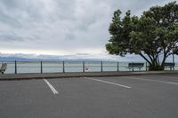 the parking lot at the pier where cars are parked and a bench with a water view