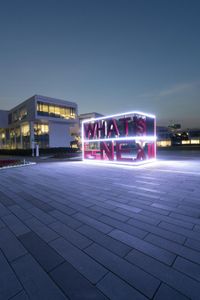 a large sign with neon letters on top of it in front of a building at dusk