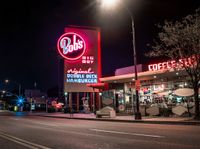 a coffee shop lit up at night on a city street with no one on it