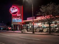 a coffee shop lit up at night on a city street with no one on it