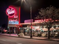 a coffee shop lit up at night on a city street with no one on it