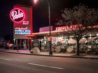 a coffee shop lit up at night on a city street with no one on it