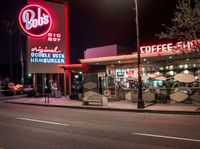 a coffee shop lit up at night on a city street with no one on it