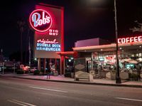 a coffee shop lit up at night on a city street with no one on it