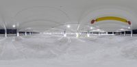 an underground parking lot with snow and neon lights on the ceiling and a walkway that leads to the parking garage area