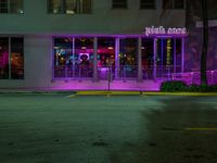 neon lights in the windows of an illuminated building in the night time on a sidewalk