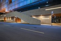 a stairway is on the side of an empty street in front of a high rise building