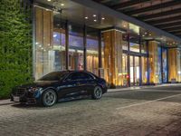 a very nice looking car parked by some nice architecture at night time with the lights on