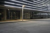 an empty parking lot with a large lighted sign next to a glass door on the side of the road