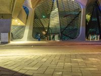 the walkway outside of a building at night with a traffic light in the foreground