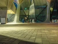 the walkway outside of a building at night with a traffic light in the foreground