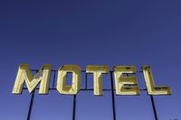 a neon sign with the word motel on it's sides in front of a blue sky