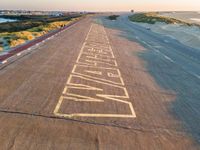 an airplane is painted on the road at sunset next to the ocean and the runway