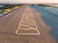 an airplane is painted on the road at sunset next to the ocean and the runway