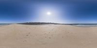 a beach that has some tracks in the sand and a bright blue sky above it