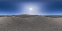 a sand hill and the sun on top of it in a circle shape over an island with people on a beach below