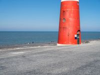 a person on a bicycle is riding next to a lighthouse on the road by the water