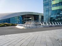 the curved concrete structure with several small statues outside of it stands out from behind the modern glass wall