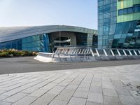 the curved concrete structure with several small statues outside of it stands out from behind the modern glass wall