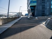 a concrete ramp going towards a building with multiple windows on it and concrete steps next to the walkway and sidewalk