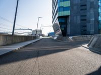 a concrete ramp going towards a building with multiple windows on it and concrete steps next to the walkway and sidewalk