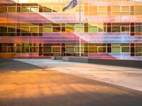 the side of a large building with a flag in front of it at sunset time