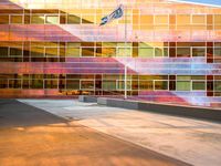 the side of a large building with a flag in front of it at sunset time