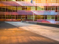 the side of a large building with a flag in front of it at sunset time