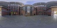 a circular building with round glass windows, and concrete walls in front of it,