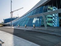 a building that has windows and a ramp outside it in a city area that is made out of glass