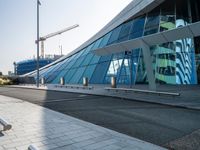 a building that has windows and a ramp outside it in a city area that is made out of glass