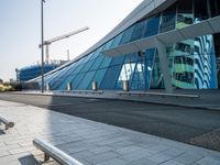 a building that has windows and a ramp outside it in a city area that is made out of glass