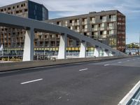 a large pedestrian bridge with lots of traffic in it's lanes, a cyclist on the bike path