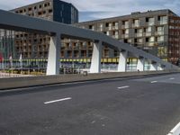 a large pedestrian bridge with lots of traffic in it's lanes, a cyclist on the bike path