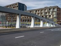 a large pedestrian bridge with lots of traffic in it's lanes, a cyclist on the bike path