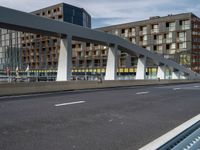 a large pedestrian bridge with lots of traffic in it's lanes, a cyclist on the bike path