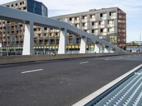 a large pedestrian bridge with lots of traffic in it's lanes, a cyclist on the bike path