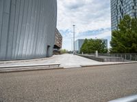 an outdoor area with some stairs, cars and buildings in the background, under a cloudy blue sky