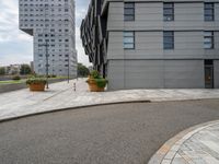 two buildings are in the distance on a city street with planters and curbing