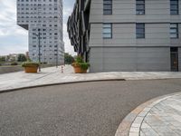 two buildings are in the distance on a city street with planters and curbing