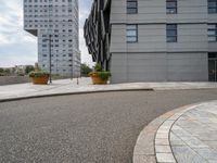 two buildings are in the distance on a city street with planters and curbing