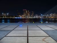 a couple of benches that are sitting in front of a body of water on a city sidewalk