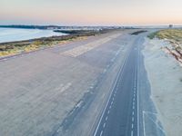 an aerial view of a roadway on a beach side highway that is paved with white lines