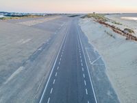 an aerial view of a roadway on a beach side highway that is paved with white lines